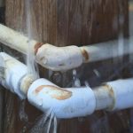 Spring Plumbing Challenges: How Leak Detection Prevents Water Damage After Thawing Leaking and corroded plumbing pipes spraying water inside wall cavity, showing damage from freeze-thaw cycles and hidden spring leaks